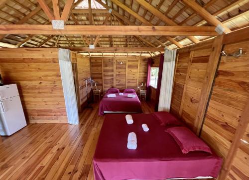 two beds in a room with wooden walls at RAIATEA - Orion Hoe Bungalow in Uturoa