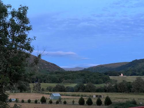 a view of a farm with mountains in the background at Carn A Chuilinn House in Fort Augustus