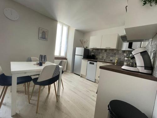 a kitchen with a white table and chairs in a room at T2 refait à neuf sur le thème oriental in Rodez