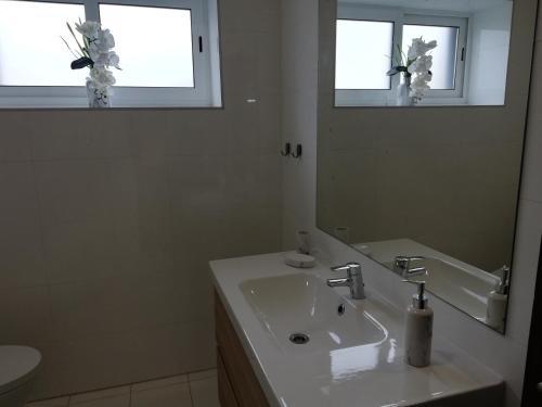 ein weißes Badezimmer mit einem Waschbecken und einem Spiegel in der Unterkunft Buddies Charm House in Aveiro