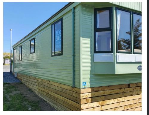 a green building with windows on the side of it at Serenity in Monreith