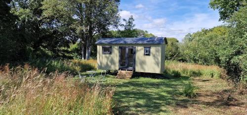 a small shed in the middle of a field at Apple Orchard Shepherd Huts in Staple Cross
