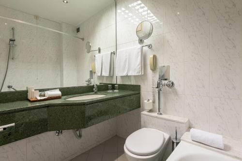 a bathroom with a toilet and a sink and a mirror at Holiday Inn Thessaloniki, an IHG Hotel in Thessaloniki