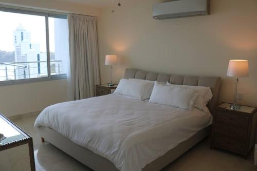a bedroom with a large bed with white sheets and a window at 14B Luxury Oceanview Playa Bonita Resort Panama in ArraijÃ¡n
