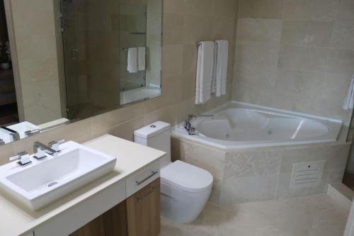a bathroom with a sink and a tub and a toilet at 14B Luxury Oceanview Playa Bonita Resort Panama in ArraijÃ¡n