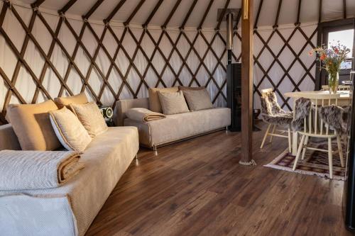 a living room with two couches in a yurt at Jurtowe Wzgórze Glamping in Grabinek