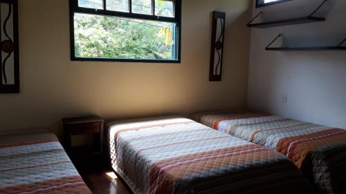 2 Betten in einem Zimmer mit Fenster in der Unterkunft Guapimirim Casa de Campo in Guapimirim