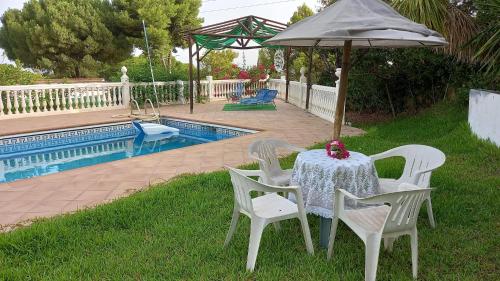 einen Tisch und Stühle mit einem Sonnenschirm neben einem Pool in der Unterkunft Villa Lucía in Alhaurín de la Torre