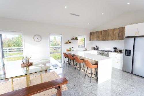 a kitchen with white cabinets and a large island with bar stools at Boundary Retreat Twizel in Twizel
