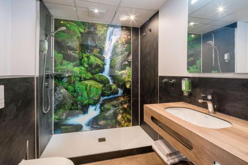 a bathroom with a waterfall mural on the wall at Best Western Plus Schwarzwald Residenz in Triberg