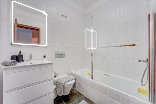 Baño blanco con bañera y lavamanos en Sea View Apartment Magic Moments Adeje en Adeje