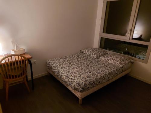 una camera con un letto e una sedia e una finestra di Appartement entier a Rennes