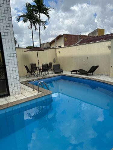 uma grande piscina azul com cadeiras e um edifício em Ap Cozy Calhau prox PRAIA em São Luís