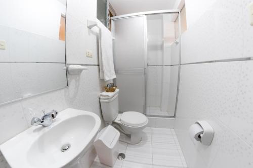 een witte badkamer met een toilet en een wastafel bij CESAR'S HOTEL PERU in Puno