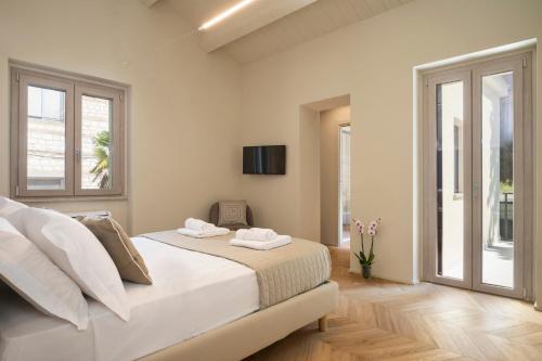 ein weißes Schlafzimmer mit einem Bett und zwei Fenstern in der Unterkunft Marna Relais in Sirolo
