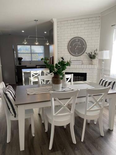 AberdareにあるHamptons House on Hunter with fire pitのテーブルと椅子と時計のあるダイニングルーム