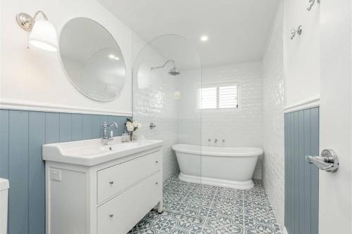 a bathroom with a sink and a tub and a toilet at Hamptons House on Hunter with fire pit in Aberdare