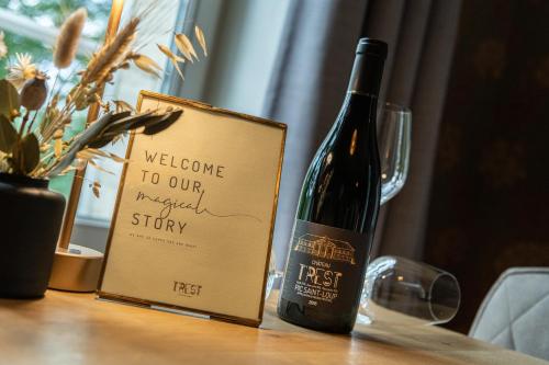 a bottle of wine sitting on a table next to a book at B&B T'Rest - Park ter Rijst in Heikruis