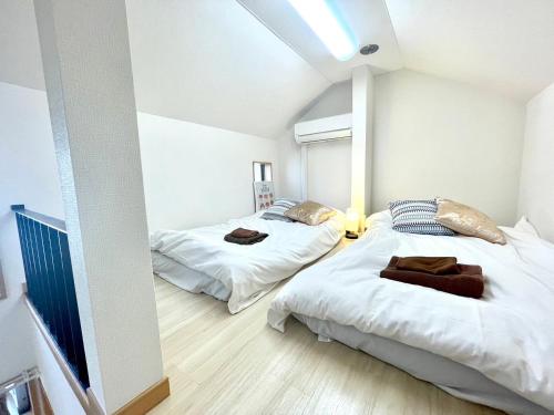 two beds in a room with white walls at 江戸川橋レジデンス EDOGAWABASHI RESIDENCE in Tokyo
