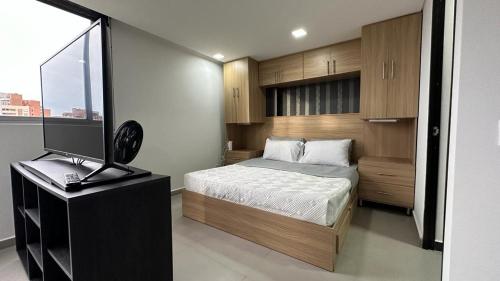 a bedroom with a bed and a desk with a television at Apartamento Panoramico en Poblado, Medellin in Medellín