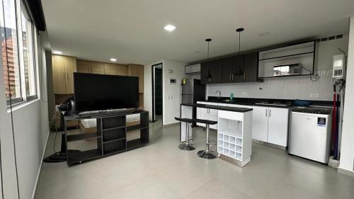 メデジンにあるApartamento Panoramico en Poblado, Medellinの大型テレビのあるキッチンと白いキャビネットのあるキッチン