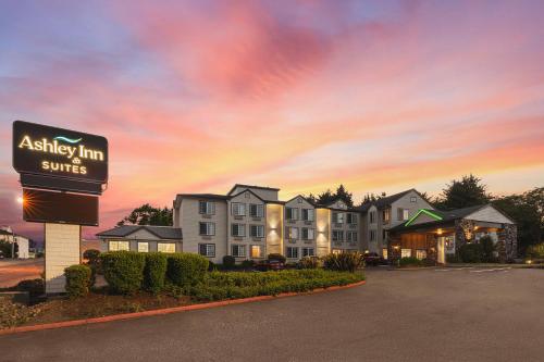 a hotel sign in front of a building with a sunset at The Ashley Inn & Suites in Lincoln City