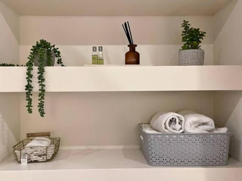 a bathroom with white shelves with towels and plants at Entire 1 bed Apartment with private Balcony in London
