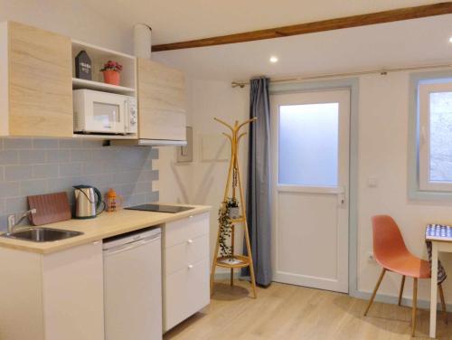 a kitchen with white cabinets and a table and a window at Maria do Mar_As Três Marias in Matosinhos