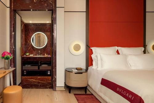 um quarto com uma cama e uma parede vermelha em Bulgari Hotel Roma em Roma