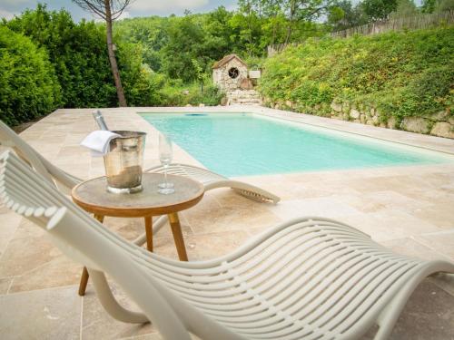 une chaise et une table à côté de la piscine dans l'établissement Gite La Folie, à Saint-Maurin
