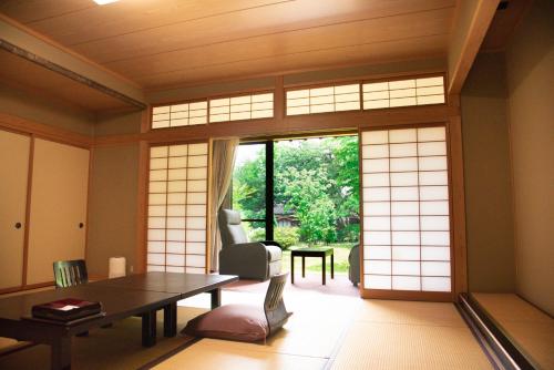 een woonkamer met een tafel en een groot raam bij Tanakaya in Kurobe