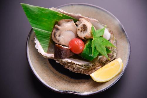 a plate of food with meat and vegetables and a lemon at Tanakaya in Kurobe