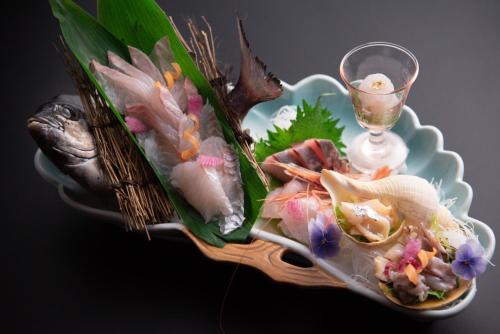 a plate of food with seafood and a glass of wine at Tanakaya in Kurobe