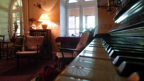 a piano in a room with a table and chairs at Hôtel Saint Jean in Vals-les-Bains