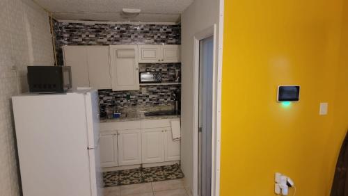 una cocina con armarios blancos y una pared amarilla en Sunrise Efficiency, en Sunrise
