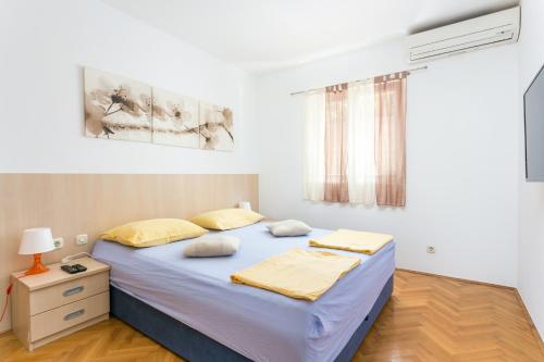 - une chambre avec un grand lit et des oreillers jaunes dans l'établissement Apartments with WiFi Makarska - 20217, à Makarska