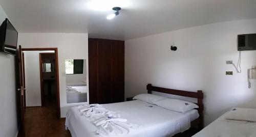 a bedroom with two beds with white sheets and a mirror at Chalés Holiday House in Rio Quente