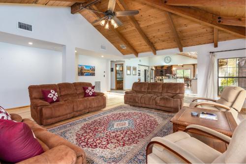 a living room with leather furniture and a wooden ceiling at Sunset Retreat- TWO houses with hot tub, firepit, multiple kitchens, sleeps 20 in Coarsegold