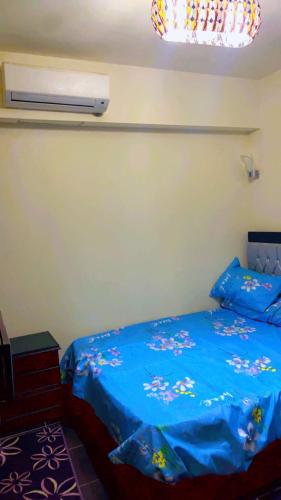 a bedroom with a bed with a blue comforter at جولف بيه برتو السخنه in As Suways