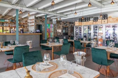 Riva Beach Club I Boutique Hotel I Restaurant في فيرا: مطعم فيه كراسي خضراء وطاولات وبار