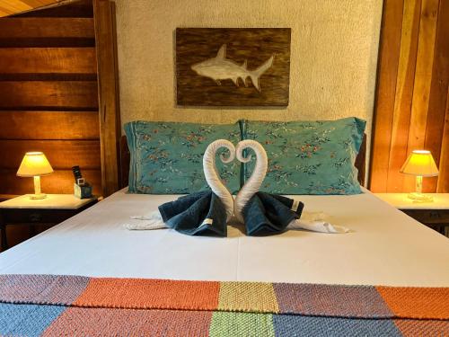 Dois cisnes feitos para parecer corações sentados numa cama. em Hotel Pousada Praia do Farol na Ilha do Mel
