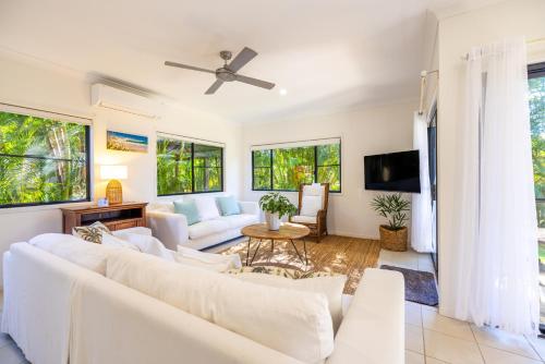 a living room with white furniture and windows at Monterey Beach House - direct beach access & plunge pool in Byron Bay