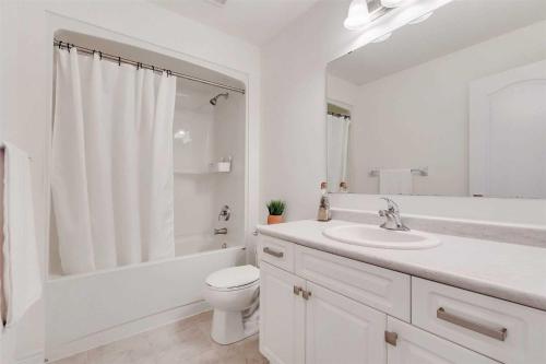 een witte badkamer met een toilet en een wastafel bij Konia Suites in Orangeville