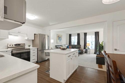a kitchen with white appliances and a living room at Konia Suites in Orangeville