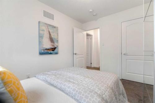 Konia Suites في أورنجفيل: غرفة نوم بسرير ولوحة قارب شراعي