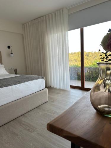 ein Schlafzimmer mit einem Bett und einem Tisch mit einer Vase darauf in der Unterkunft Villa Deluxe - Quinta do Outeirinho in Celorico de Basto