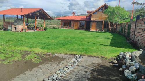 ein Haus mit einem Rasenplatz und einem Gebäude in der Unterkunft Rancho Descanso in Guano