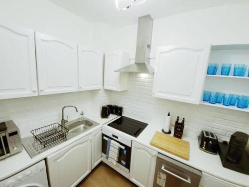 a white kitchen with white cabinets and a sink at Prime London Living 2-Bedroom Beauty! in London