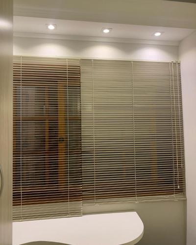 a bathroom with a large window with wooden blinds at Moradia Compartilhada Pelotas in Pelotas