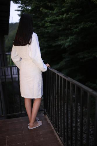 a woman in a white dress standing on a fence at Yeghevnut Hotel in Goris